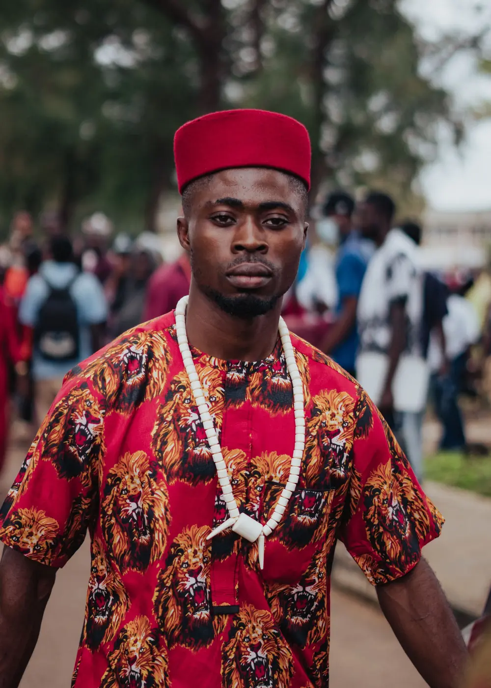 A young Igbo man in a red cap and lion print isiagu with ivory beads