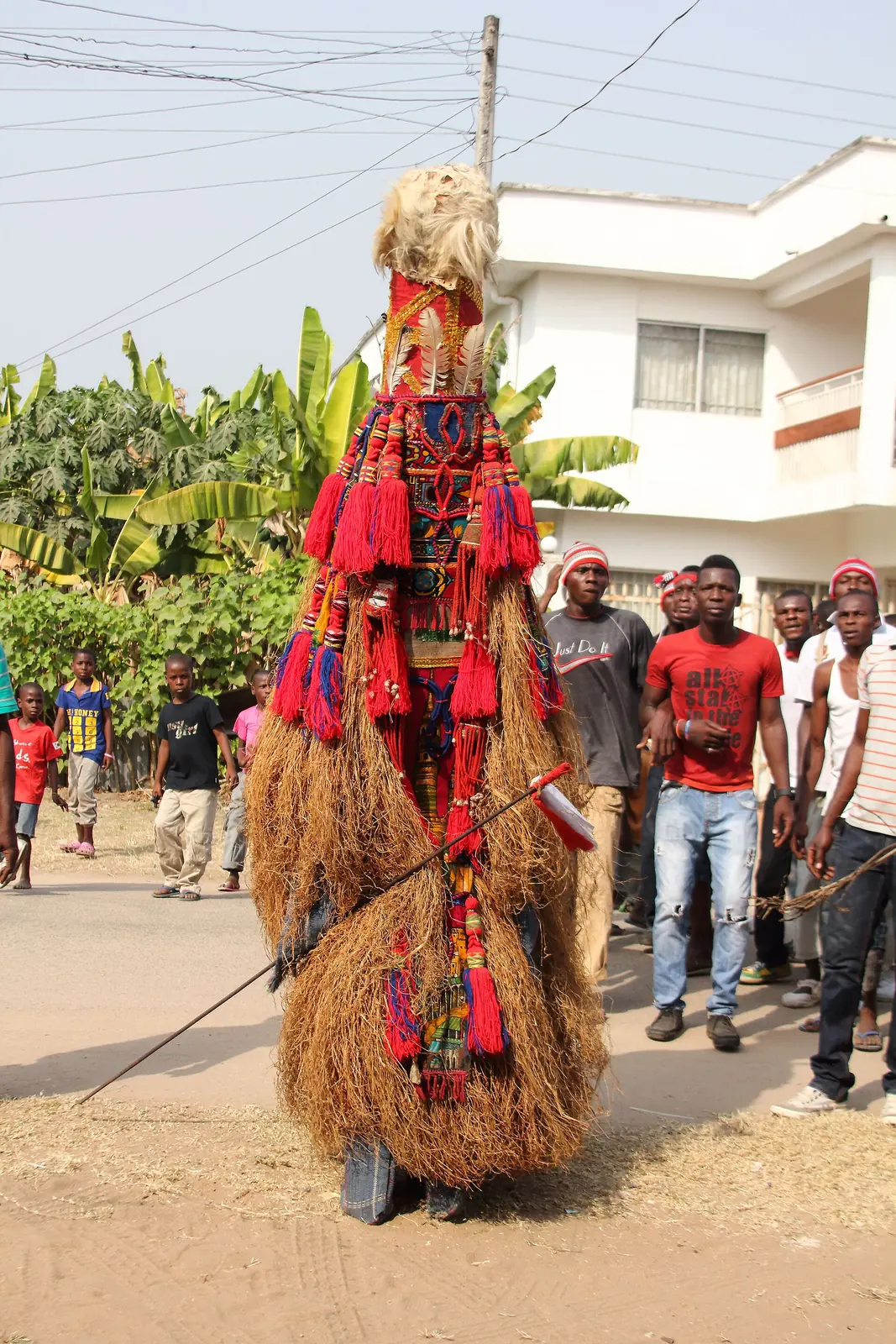 An Mmanwu masquerade in raffia and red cloth